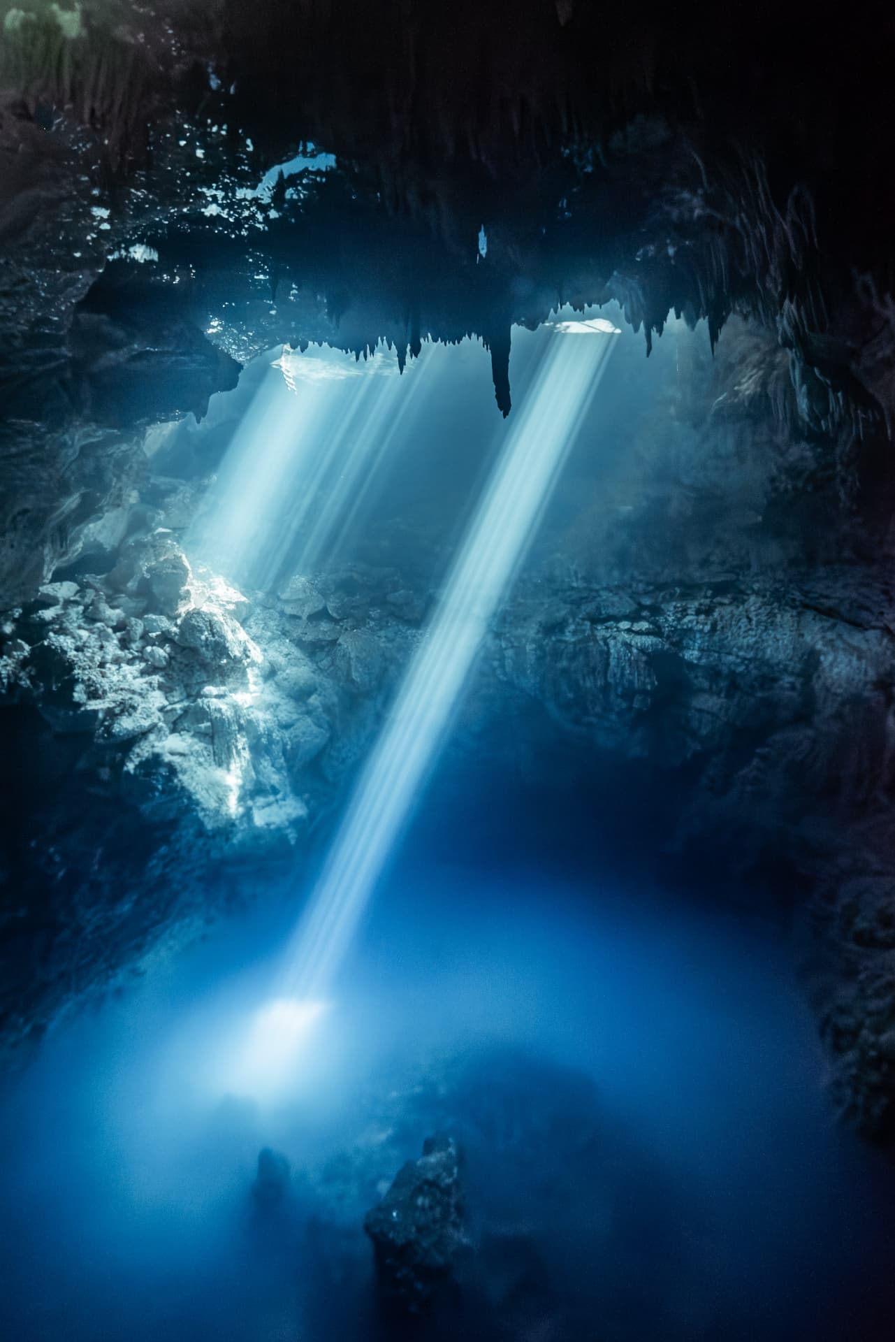 Light beams falling through clear cenote water near Tulum, Mexico