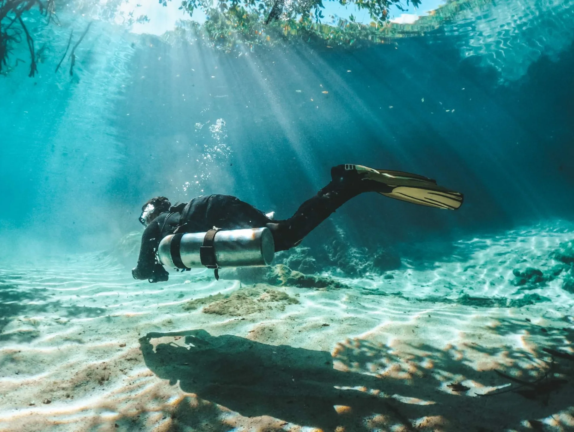 Diver above a rippled sandy floor at Casa Cenote