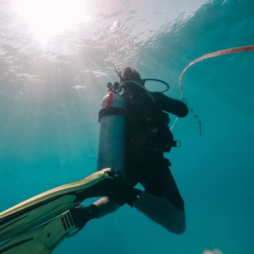 Diver holding a guideline in bright, clear water below the surface