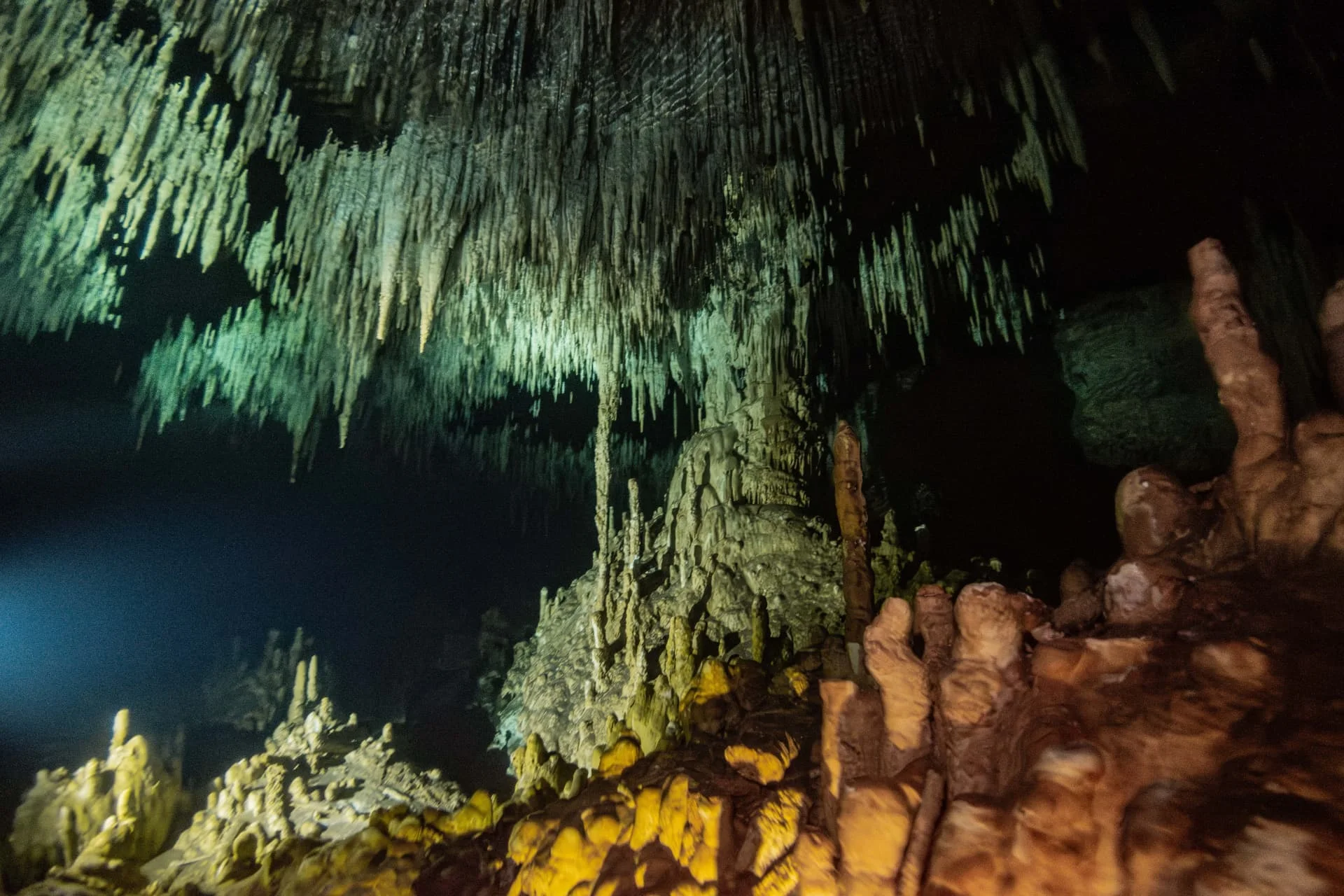 Dense limestone stalactites and stalagmites illuminated inside Dreamgate