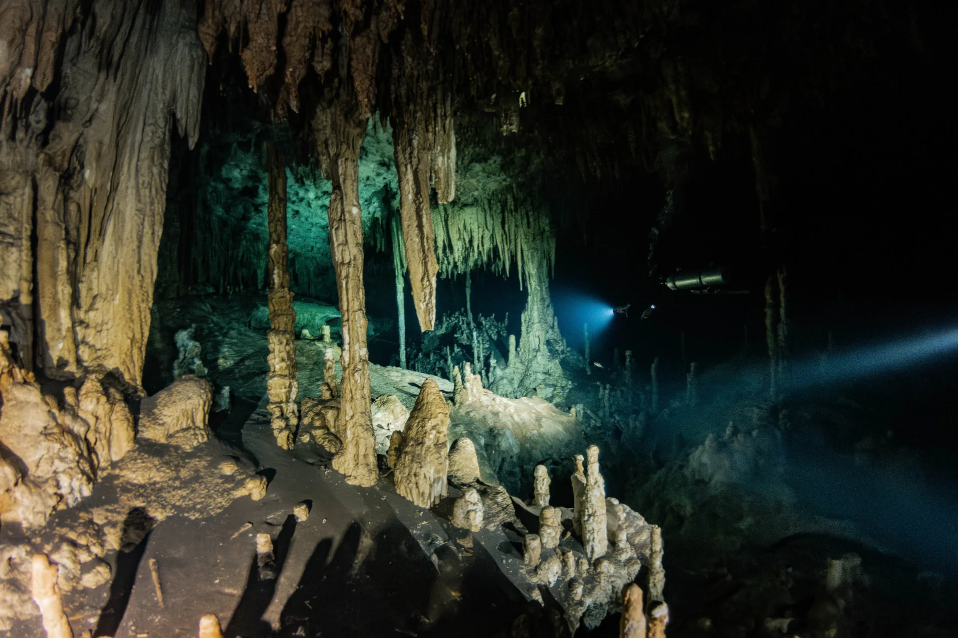 Diver illuminating dense stalactites and stalagmites inside Dreamgate